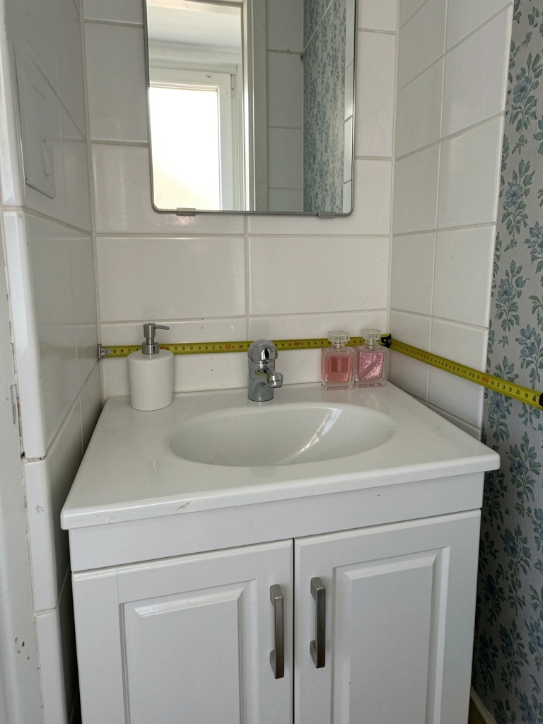 Trena amarela estendida sobre bancada de banheiro compacto com azulejo branco