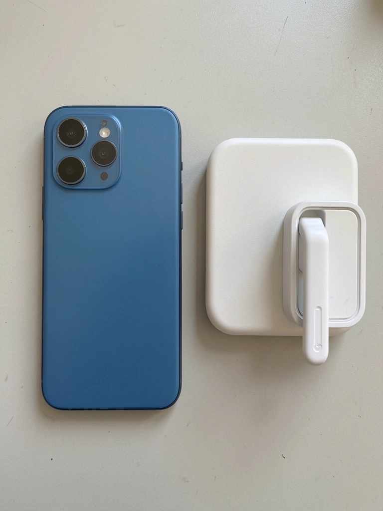 Carregador magnético branco acoplado à parte traseira de um iPhone sobre mesa de madeira clara